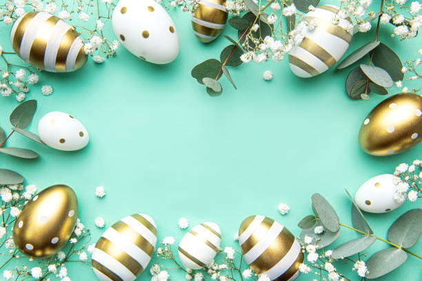 istock Easter eggs painted in gold and eucalyptus branches on a soft green background. 1473623451
