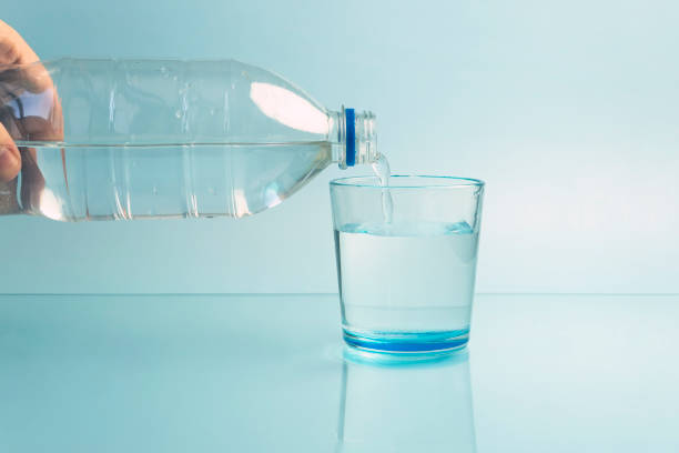 istock Pouring water from bottle into glass blue background 1473623672