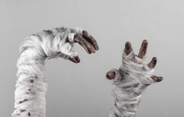 istock Mummy hands wrapped in a bandage isolated on a black background. Halloween concept 1473624534