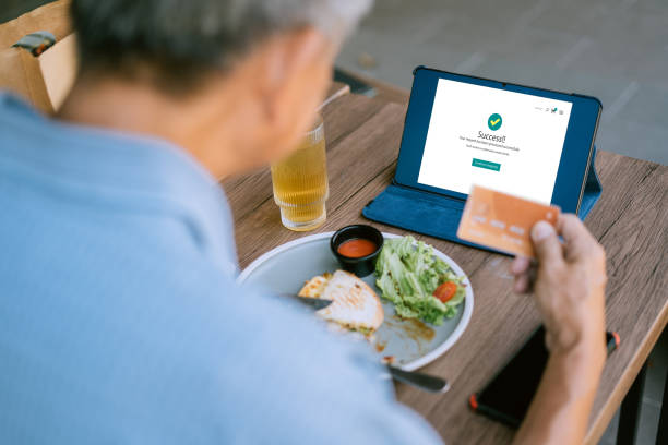 istock Digital Inclusion: Senior Asian Citizen Adopts Technology for Seamless Online Transactions in a Cafe 1473625235
