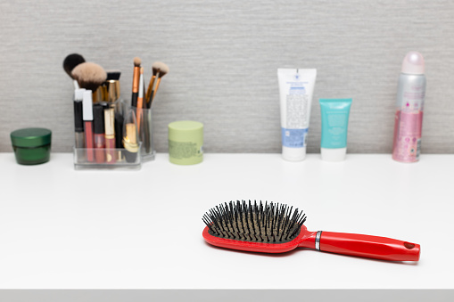 old used hairbrush on the table with cosmetics. an old comb with sticking hair lies on the table. old comb with hair.