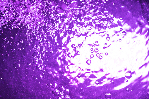 Pure water in the bathtub with neon backlight. Artistic water background