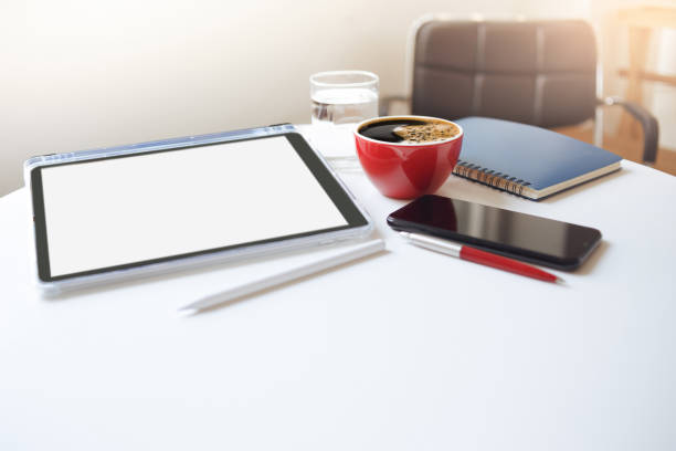 Desk work coffee cup with smart phone and tablet computer, notebook, pen on white table, Freelance working part time in cafe