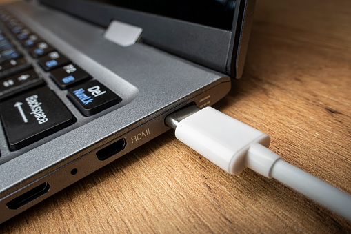 Cable USB adapter under the Type-C connector is installed in the laptop against the background of a wooden table