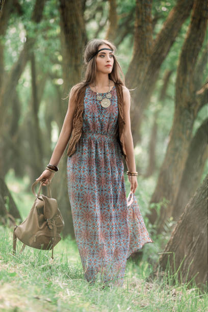 attractive young hippie woman walking among trees in forest stock photo
