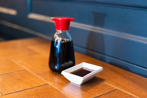Soy sauce bottle, sauceboat bowl dish of soy sauce on wooden table, selective focus