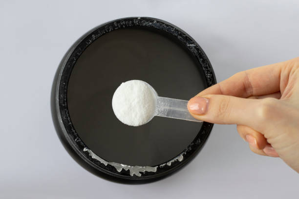 istock Black can with white BCAA powder in a measuring spoon in a woman's hand on a white background, top view. Amino acids, muscle building, fitness, workout. 1473632218