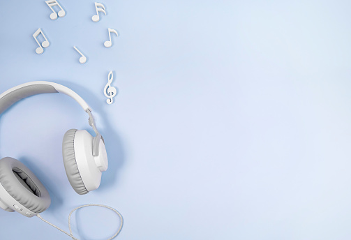 Headphones with notes on a blue background. The concept of listening to music.