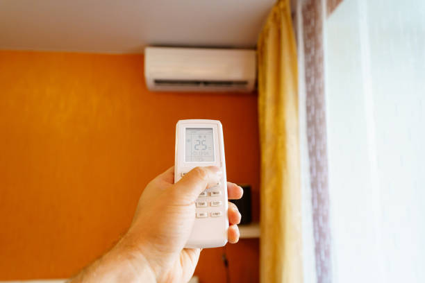 istock hand with the remote control of the air conditioner. 1473633806
