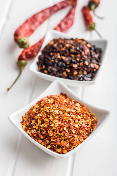 istock Dry chili pepper flakes. Crushed red peppers in bowl on white table. 1473634580