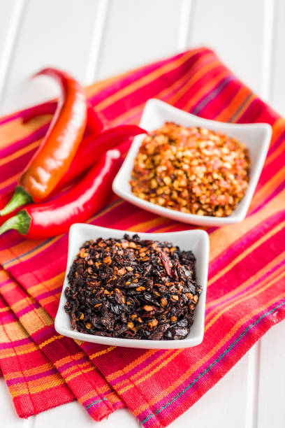 istock Dry chili pepper flakes. Crushed red peppers in bowl on white table. 1473634643