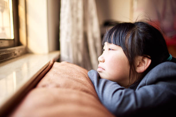 istock Little girl with frustrated expression looking out the window 1473634900