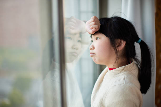istock Little girl with frustrated expression looking out the window 1473635020
