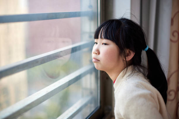 istock Little girl with frustrated expression looking out the window 1473635053