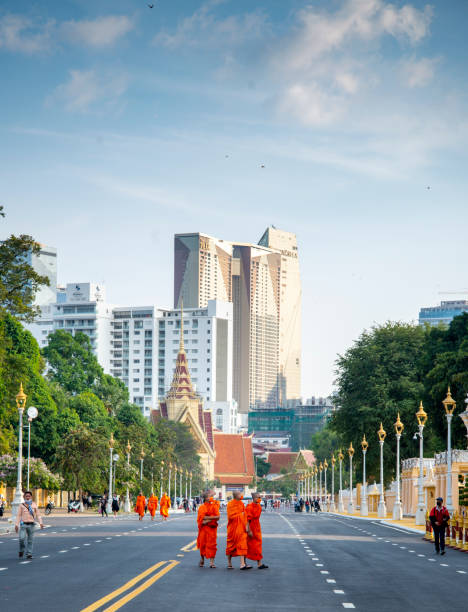 monges budistas caminham ao longo da avenida do palácio real, na capital do camboja. - phnom penh - fotografias e filmes do acervo