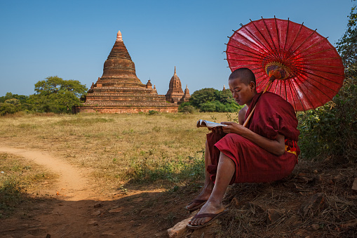 Young Burmese girl with thanaka face paint looking at an ancient temples of Bagan, Myanmar (Burma)