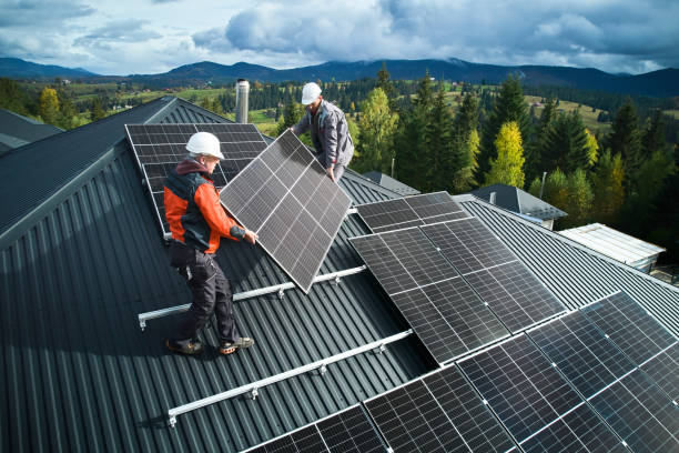 istock Technicians carrying photovoltaic solar module while installing solar panel system on roof of house 1473638776