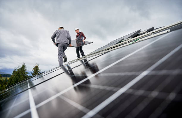 istock Technicians carrying photovoltaic solar module while installing solar panel system on roof of house 1473638838