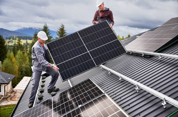 istock Technicians carrying photovoltaic solar module while installing solar panel system on roof of house 1473638844