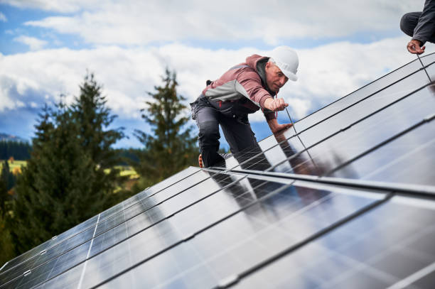Technicians installing photovoltaic solar panels on roof of house. stock photo