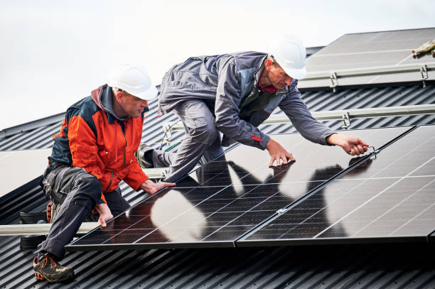 Technicians installing photovoltaic solar panels on roof of house. stock photo