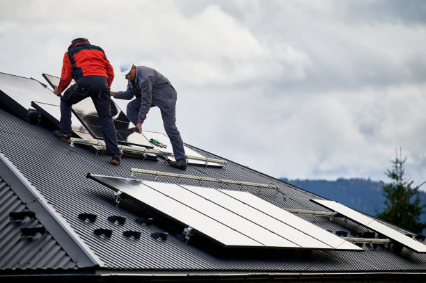 istock Technicians carrying photovoltaic solar module while installing solar panel system on roof of house 1473638945