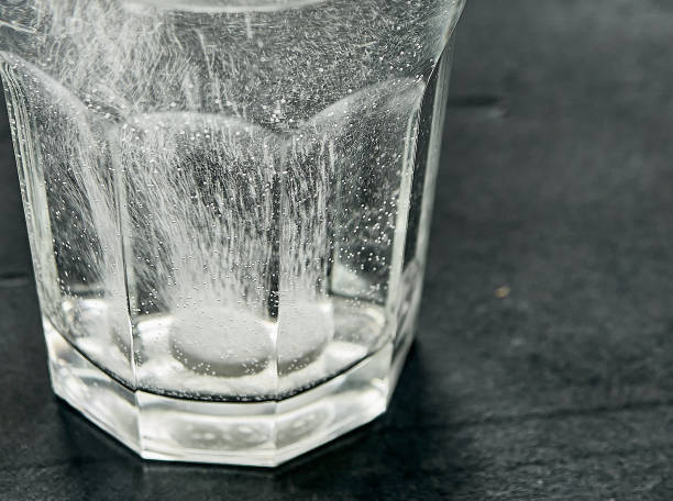 istock White effervescent tablet in glass with water on table. 1473639228