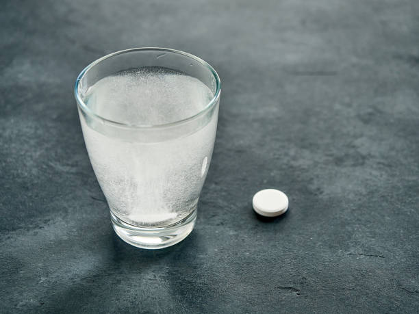 istock White effervescent tablet in glass with water on table. 1473639242