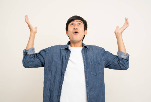 istock Handsome young man age around 25 smiling and happy pointing copy space. Charming male standing with on isolated white background. Asian people pose  with white backdrop. 1473641592