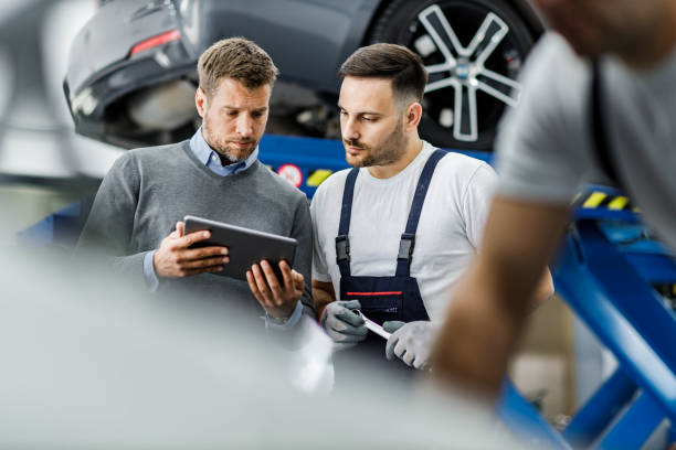 istock Male customer and auto mechanic using touchpad in a workshop. 1473643071
