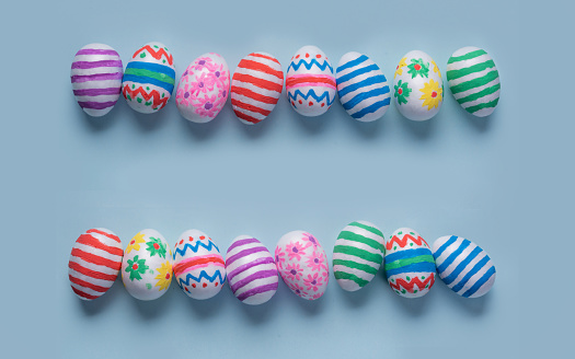 Colorful hand-decorated Easter eggs on a light blue background, arranged in two horizontal rows with copy space for a personalized Easter message. Use as a background for a banner or Easter card