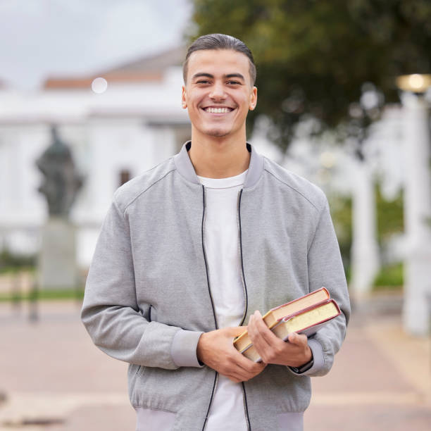 istock Study, books and student portrait at university, college or campus for research, knowledge and scholarship motivation. Happy young man with outdoor learning for exam, studying and reading inspiration 1473644582