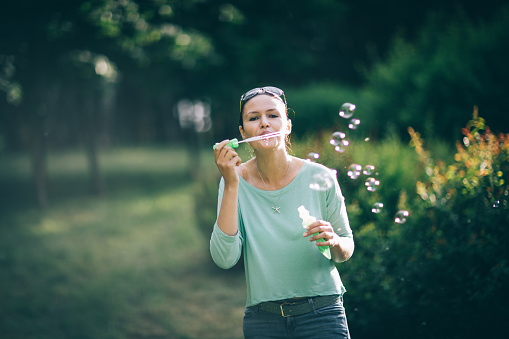 attractive young woman playing with soap bubbles in summer Park. photo with copy space