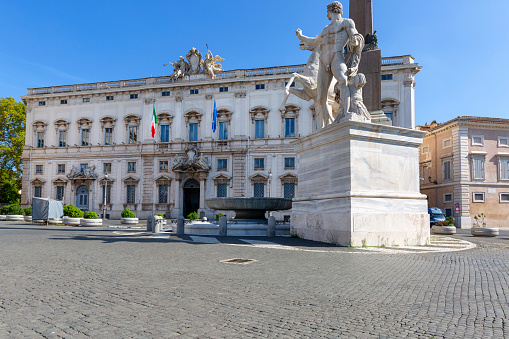 A beautiful wide view of the Piazza del Quirinale (Quirinal Square) with the facade of the Palazzo della Consulta on the left, seat of the Constitutional Court of the Italian Republic, and the Fountain of the Dioscuri, Castor and Pollux, on the right, coming from the Baths of Constantine, dating back to the Imperial Roman era. The Palazzo della Consulta, built on the Quirinal Hill in Baroque style between 1732 and 1737 at the behest of Pope Clement XII, has hosted various Italian institutions over the centuries, until it became the seat of the Constitutional Court in 1955, the highest court in Italy in matters of constitutional law. In 1980 the historic center of Rome was declared a World Heritage Site by Unesco. Super wide angle image in High Definition format.