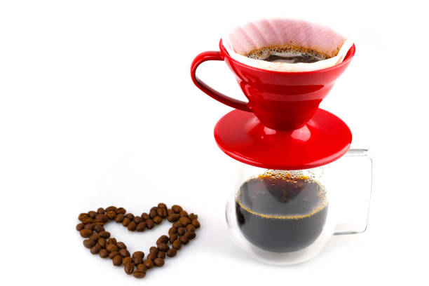 istock dripping coffee in red drip cup and the coffee water flows into the clear coffee cup below and there are coffee bean with heart shape design beside,  isolated on white background 1473649701