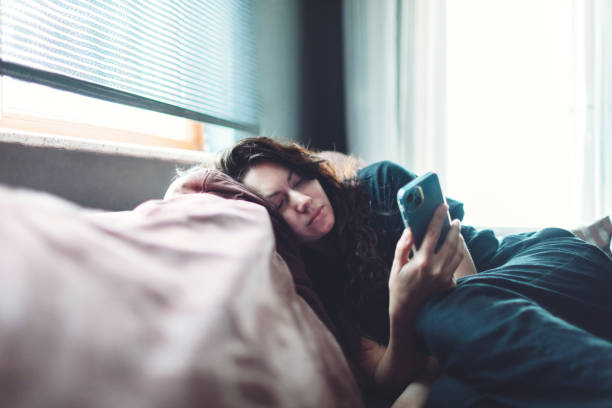 istock Depressed woman lying down on sofa at home with mobile 1473651033