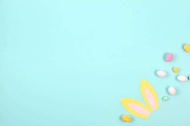 istock Easter Colorful candy chocolate eggs and paper bunny ears on pastel blue background. Easter holiday and tradition concept. 1473651052