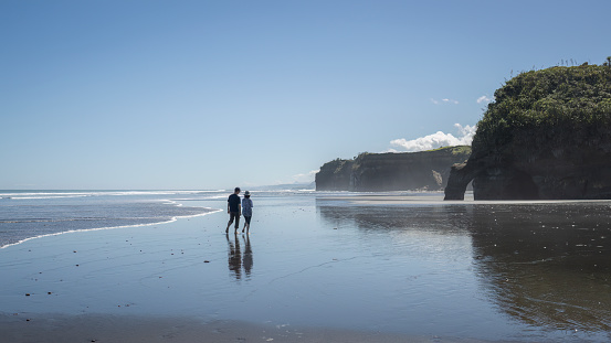 Couple walking on the beach. Amazing rock formations at Tongaporutu beach. Taranaki. New Zealand.