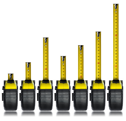Group of seven tape measures forming a bar graph isolated on white background.