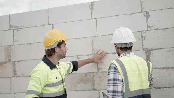 istock Team civil engineer or building architect wearing safety uniform and helmets, discussing about details of building design and construction materials of house styles and inspect construction progress at real estate sites. Building construction industry. 1473652658