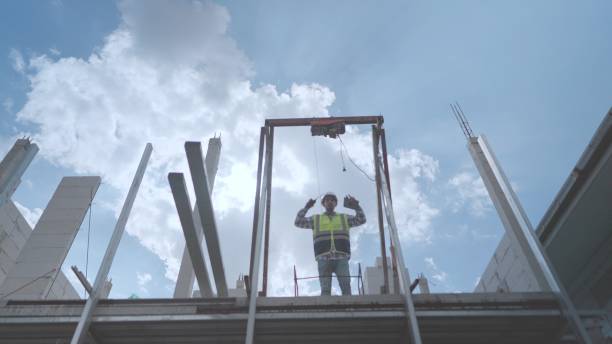 istock Civil engineer or contractor working, control the movement of construction materials from high-rise buildings on city construction site. Foreman wearing safety uniform and helmets, construction supervision at housing construction building or condominium. 1473652778