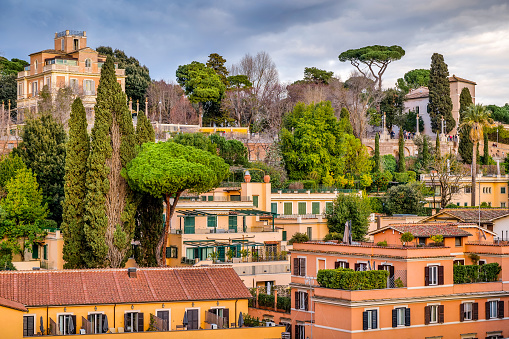 A suggestive and idyllic view over the rooftops and terraces of the Piazza di Spagna neighborhood (Spanish Steps Square district), in the historic heart of Rome. In the upper part of the photo, the famous Pincio Gardens, one of the most visited and loved places in Rome, the culmination of the west side of Villa Borghese, the largest public park in the Italian capital. From the Belvedere of the Pincio Gardens you can enjoy a breathtaking 180-degree view of the historic center of Rome, in the setting of some of the most beautiful gardens in the city. In 1980 the historic center of Rome was declared a World Heritage Site by Unesco. Image in high definition quality.