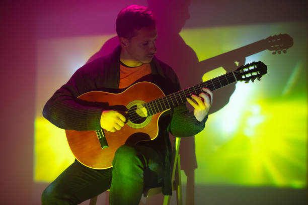 musician playing acoustic guitar in a foggy club with colorful lights. - fingerstyle imagens e fotografias de stock