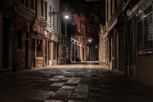 Small abandoned alley at night, city lights, closed stores