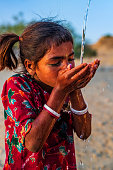 istock Indian little girl drinking fresh water, desert village, Rajasthan, India 1473659106