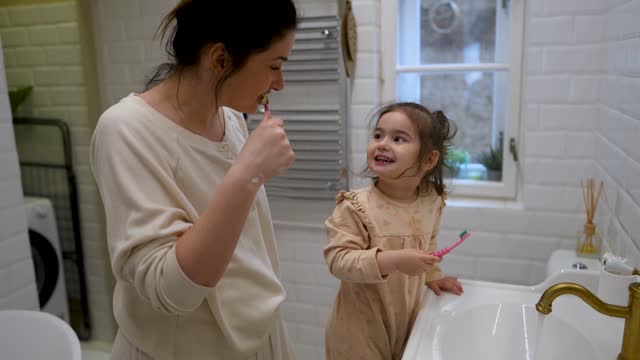 Morning routine: Little girl brushing teeth with her mom