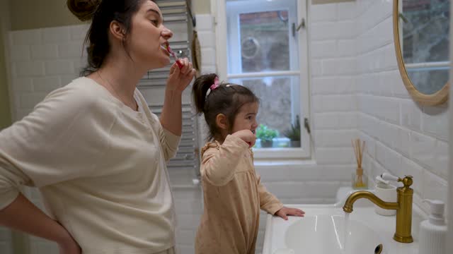 Morning routine: Little girl brushing teeth with her mom