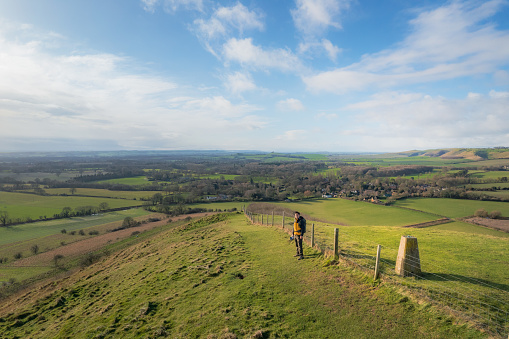 backpacker walking on footpath, beautiful hill and landscape near Pewsey, South of England, United Kingdom, winter daytime