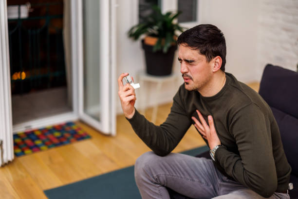 istock A man with breathing problems is using an asthma inhaler in the living room. 1473663664