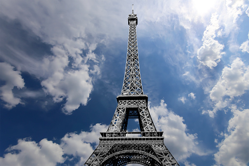 Eiffel Tower against the backdrop of the Champe de Mars park, city-line and blue sky